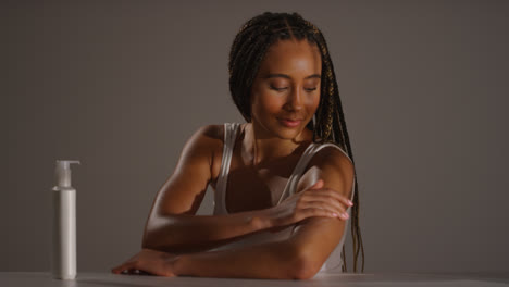 Studio-Skincare-Beauty-Shot-Of-Young-Woman-With-Long-Braided-Hair-Putting-Moisturiser-Onto-Arm-And-Shoulder-3